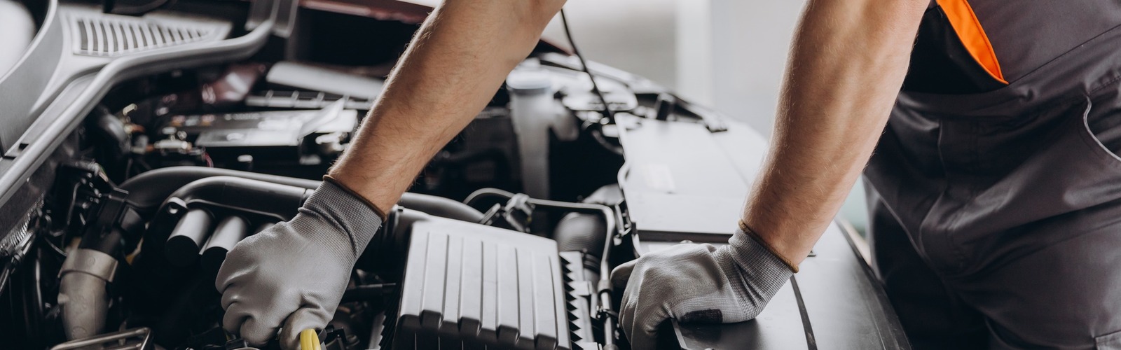 Mechatroniker schraubt am Motor eines Autos herum.