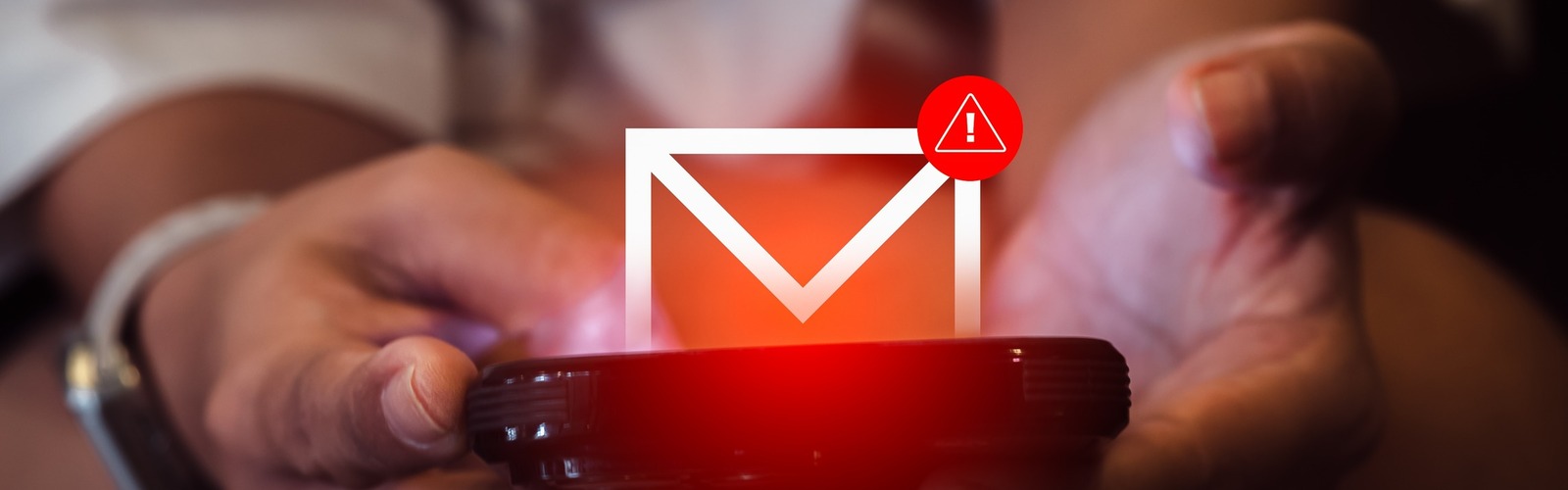 Zwei Hände halten ein Smartphone, über dem ein Mail-Symbol mit Warnhinweis schwebt