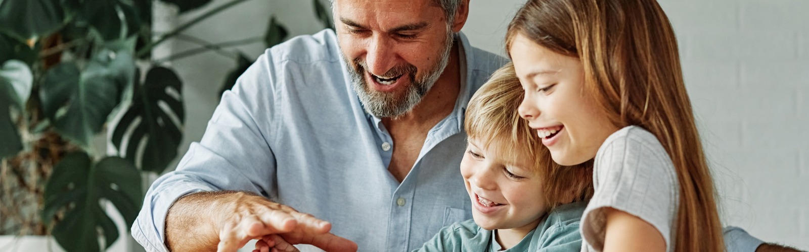 Großvater sitzt mit Enkeln vor einem Sparschwein