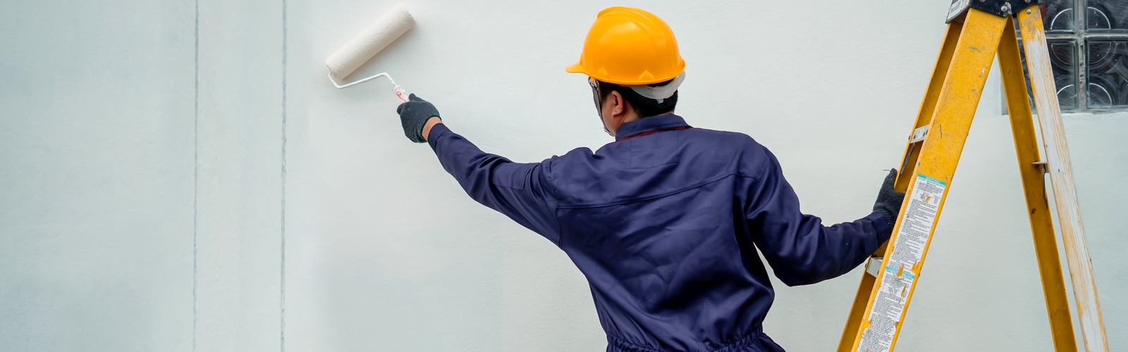 Maler streicht eine Hauswand
