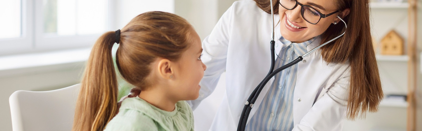 Ärztin behandelt mit Stethoskop ein Kind
